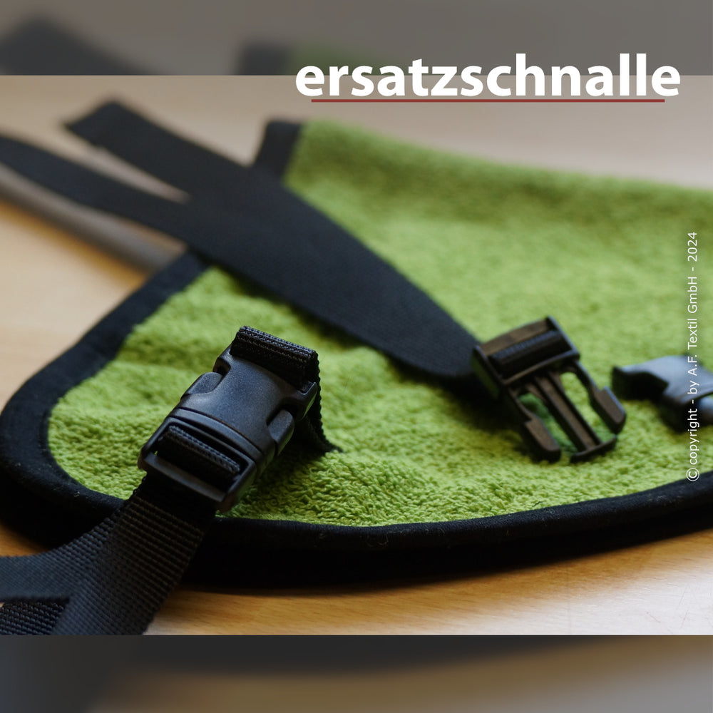 Schwarze Ersatzschnalle aus Kunststoff auf grünem gepolstertem Untergrund mit zwei verstellbaren Riemen.