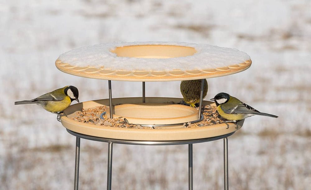 Vogelfutterhaus CeraNatur mit Ständer, rund und schneebedeckt, Meisen füttern sich daran.