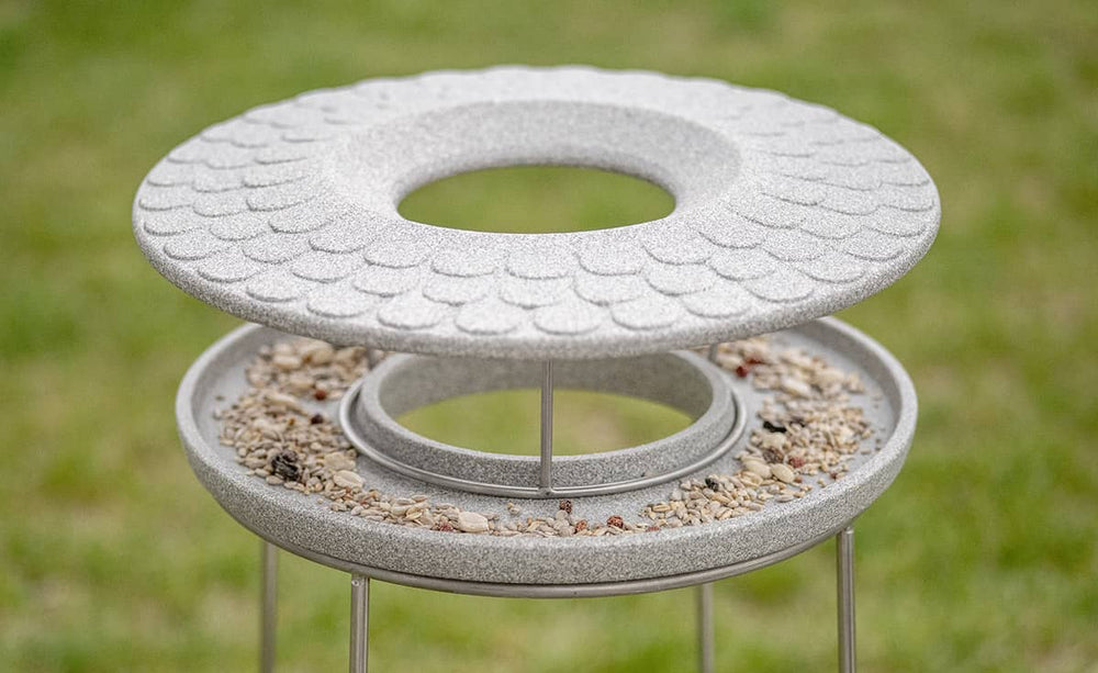 Modernes Vogelbad aus grauem Material mit strukturierten, runden Ebenen für Vögel im Garten.