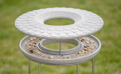 Modernes Vogelbad aus grauem Material mit strukturierten, runden Ebenen für Vögel im Garten.