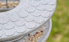 Graues Futterhaus Granicium mit Ständer und Samen auf der Plattform, vor unscharfem grünem Hintergrund.