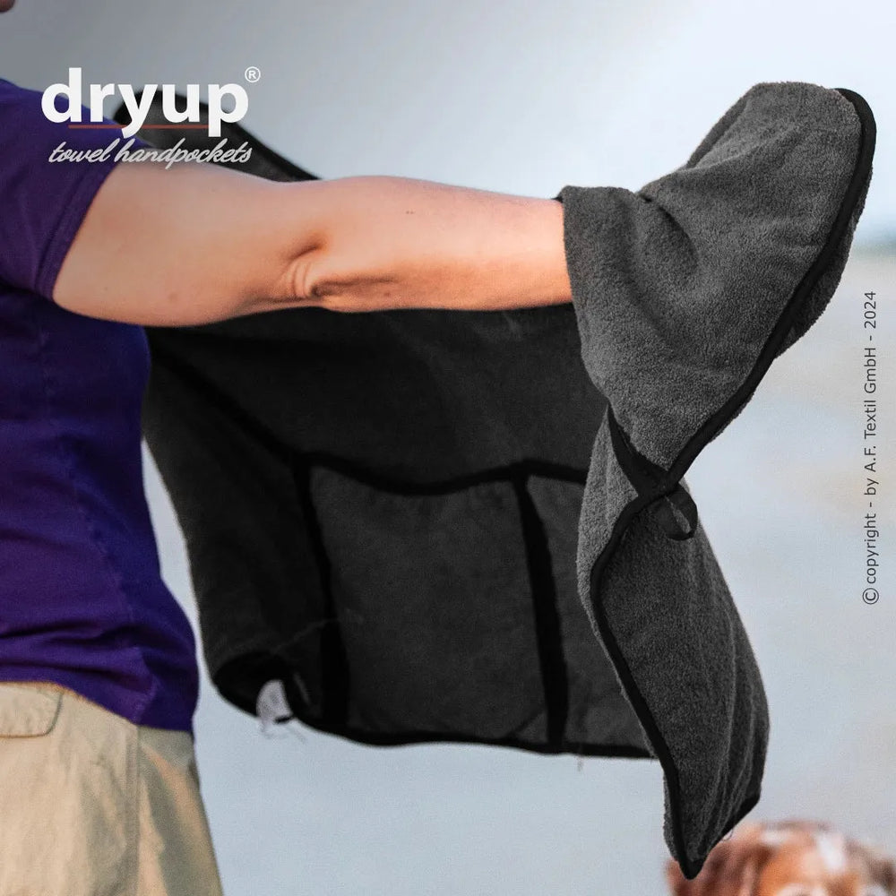 Person trägt grauen Dryup® Handtuchhandschuh mit praktischem Einsatz zum Abtrocknen, verschwommener Hintergrund.