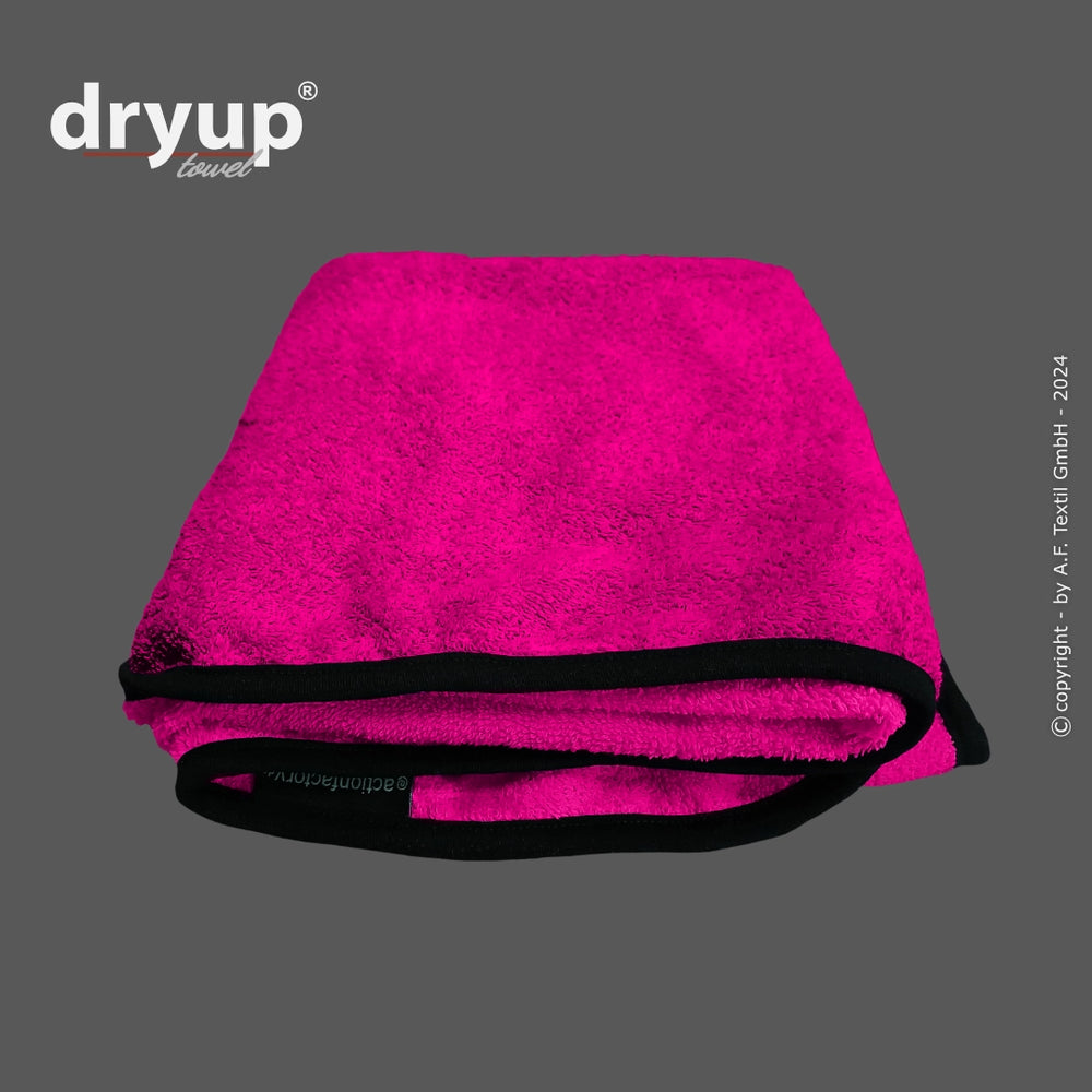 Fuchsia-farbenes Dryup® Handtuch mit schwarzen Rändern, weich und flauschig, faltbar für optimalen Gebrauch.