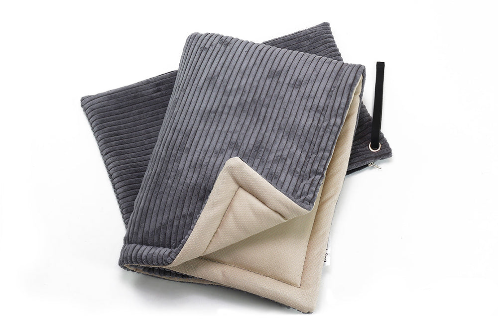 Gefaltete Hundereisedecke in dunkelgrau und beige mit softem, elegantem Material und ribbeligem Muster.