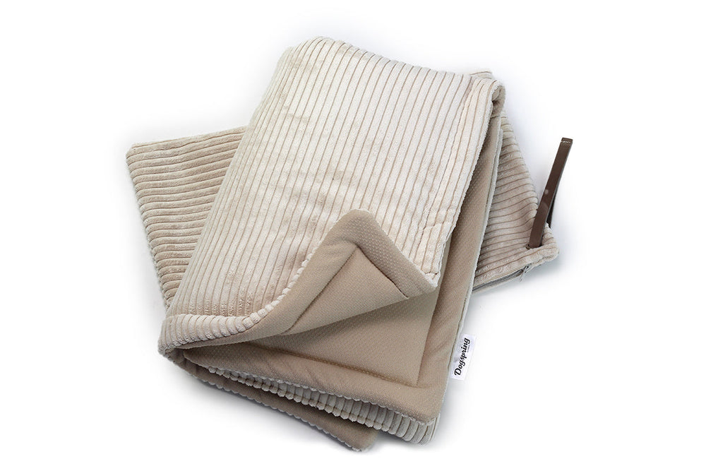 Kuschelige Hundereisedecke aus Cord in sanften Beigetönen, gefaltet, mit gerippter und glatter Oberfläche.