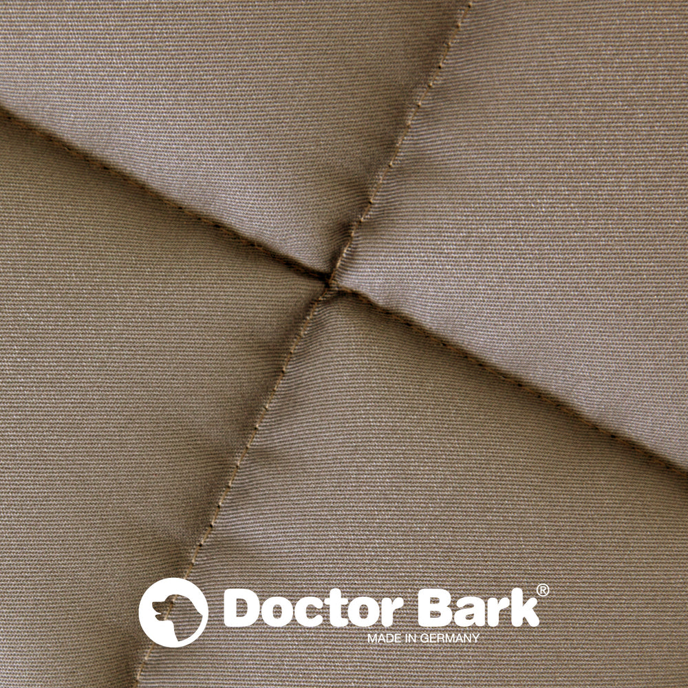 Beige gepolsterte Doctor Bark Hundedecke mit geometrischer Steppung und Logo in der unteren Hälfte.