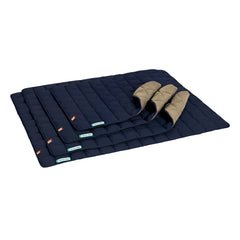 Faltbare blaue Isomatte mit beigen Kopfkissen, quiltierte Oberfläche, kompakt zusammengefaltet, ideal für Reisen.