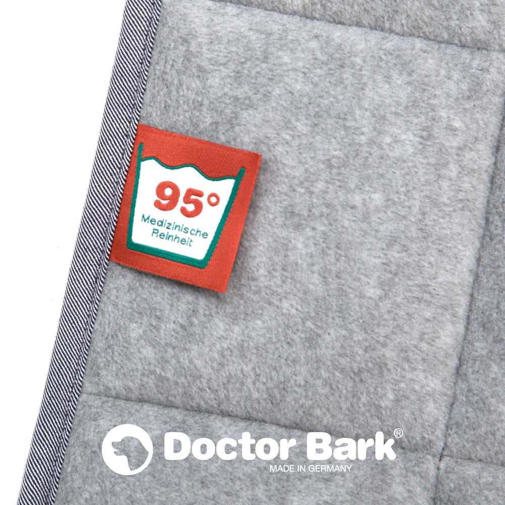 Graue Fleece Steppdecke mit rot-grüner Etikette zur medizinischen Reinheit und Doctor Bark Logo.