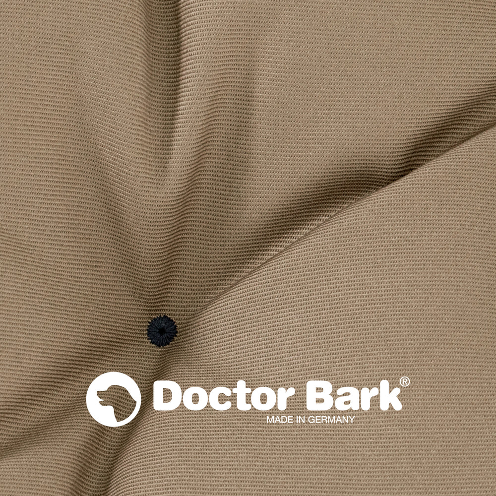 Beiges, strukturiertes Country-Kissen von Doctor Bark mit schwarzem Knopf und dem Logo "MADE IN G".