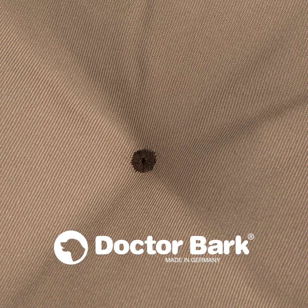Beige Lounge-Kissen von Doctor Bark mit feiner Rippstruktur und dunklem Punkt, "Made in Germany"-Logo.