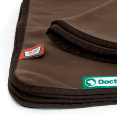 Braune Doctor Bark Kuscheldecke aus Fleece mit buntem Logo-Etikett in der Ecke.