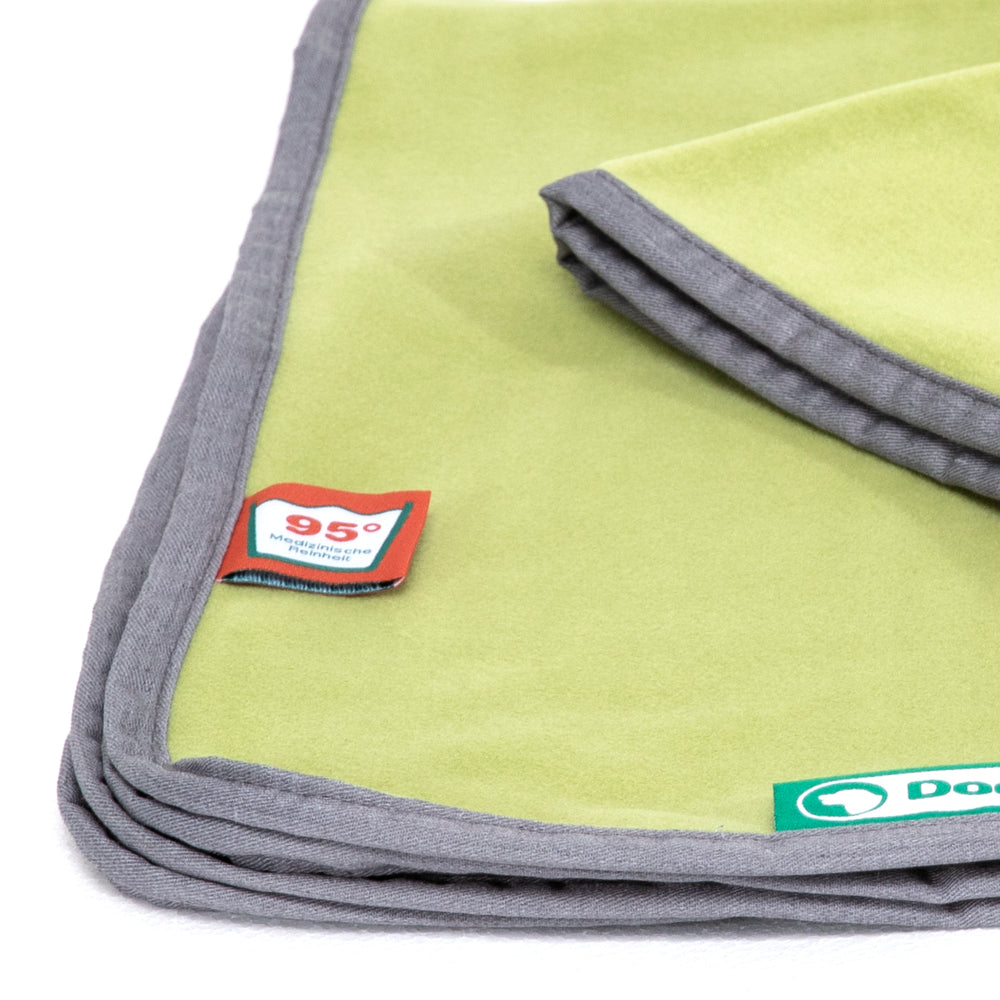 Grüne Fleece-Decke mit grauem Rand und Pflegeetikett für 95 °C, ideal zum Kuscheln und für Haustiere.