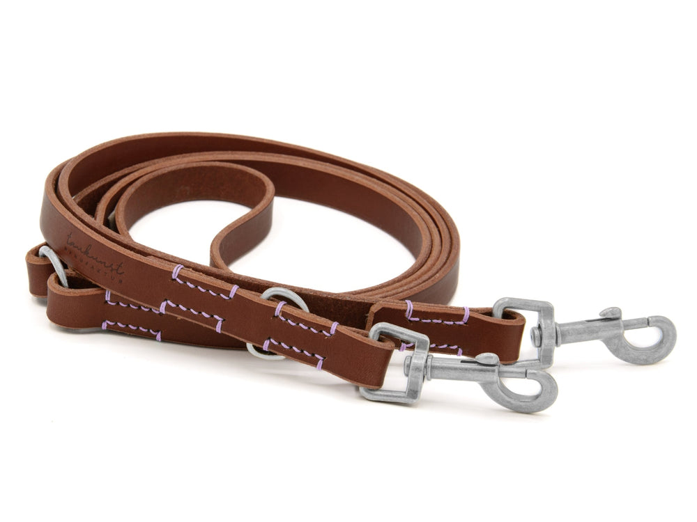 Braune Lederleine mit lilafarbener Naht und zwei Metallhaken, ideal für Hunde und stilvolle Spaziergänge.