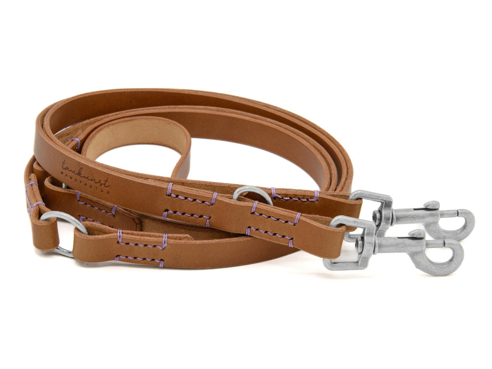 Braune Lederleine mit lila Nahtdetails und stabilen Metallkarabinerhaken für sicheren Halt. Ideal für Hunde.