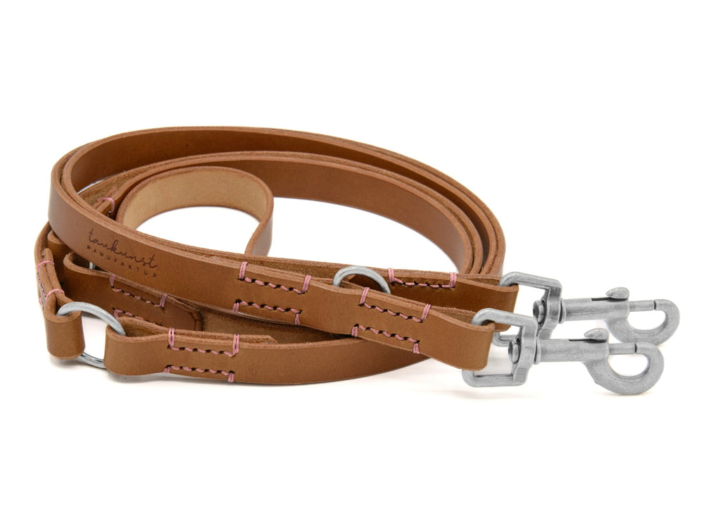 Hundeleine aus braunem Leder mit zwei Karabinerhaken und kontrastfarbigen Nähten, ideal für Spaziergänge im Freien.