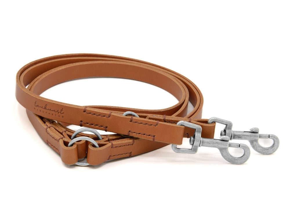 "Braune flache Lederleine für Hunde mit zwei Metallkarabinern und sichtbaren Nähten."