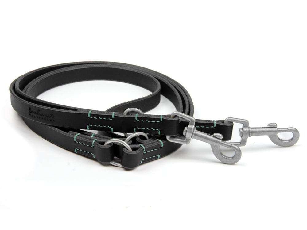 Schwarzes Lederhundehalsband mit grünen Nähten und Metallkarabinerhaken für sichere Befestigung.