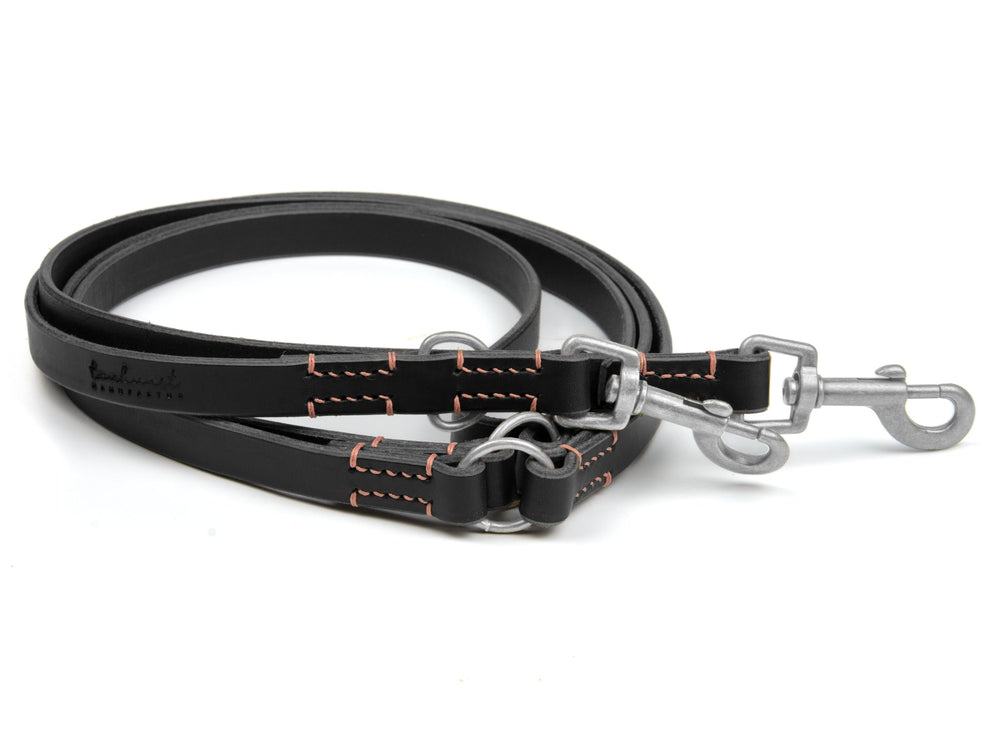 Schwarze Lederleine mit orangefarbenen Nähten und zwei Karabinerhaken, robust und flach für Hunde.