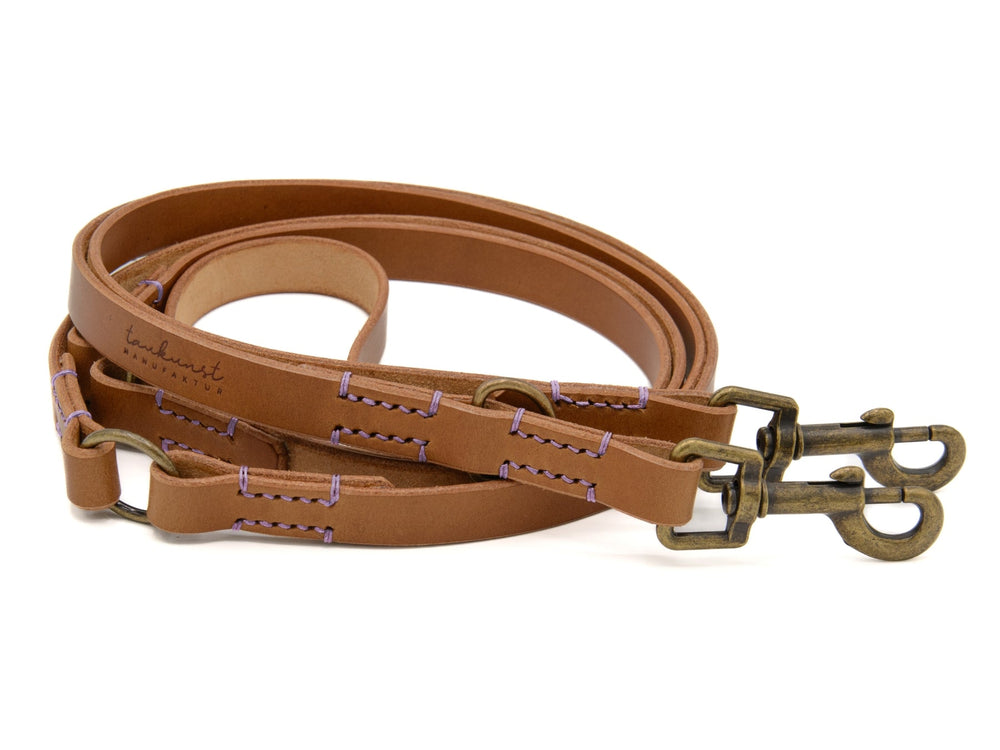 Elegante braune Lederleine für Hunde mit messingfarbenen Karabinerhaken und lila Fadeneinfassungen.