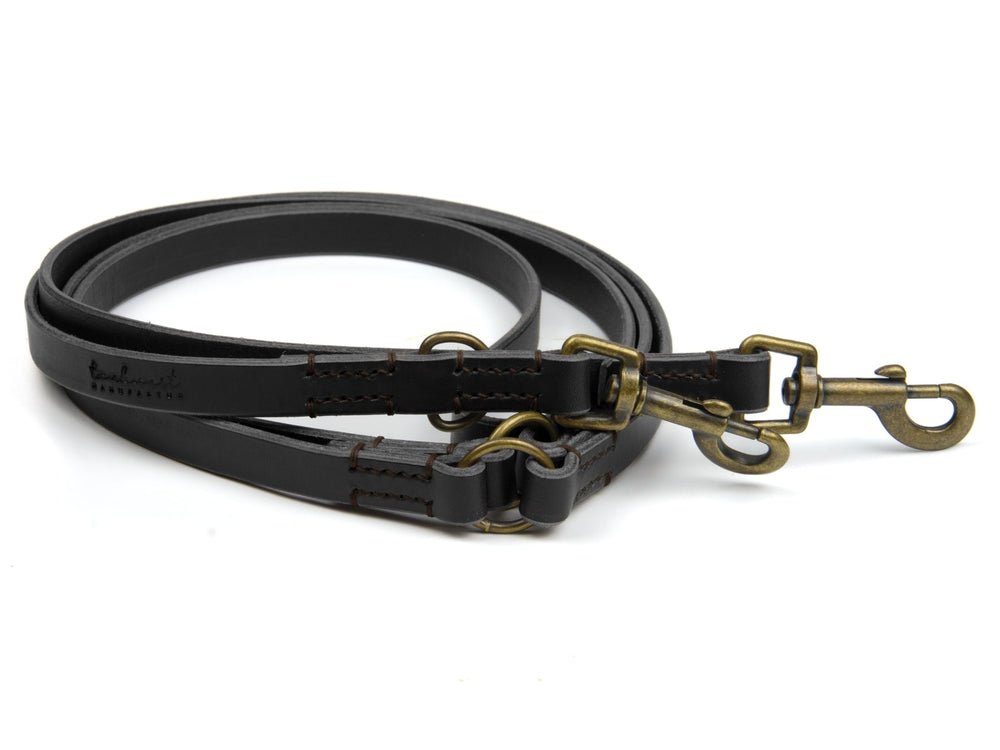 Braune Lederleine mit zwei Karabinern und verstellbaren Ringen, sorgfältig verarbeitet für besten Halt und Komfort.