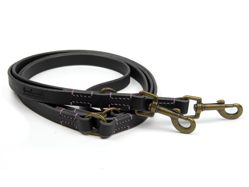Schwarze Lederleine mit lila Nähten und zwei Karabinerhaken für Hundehalter. Ideal für sicheres Spazierengehen.