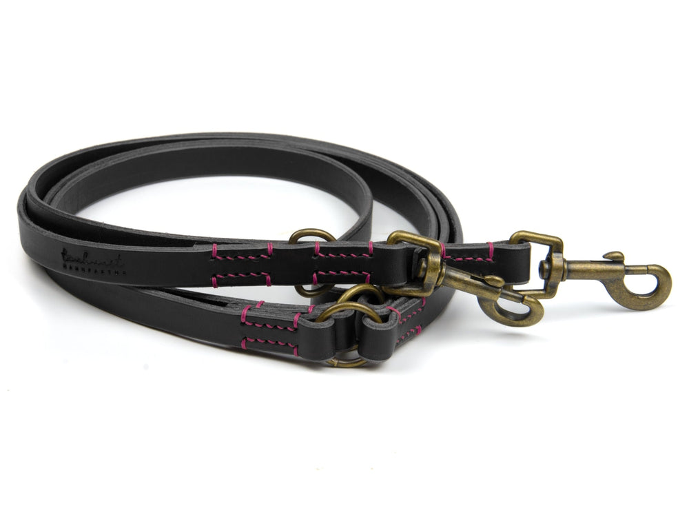 Schwarze Lederleine mit pinken Nähten und verstellbaren Ringen für Hunde, ausgestattet mit zwei Karabinerhaken.