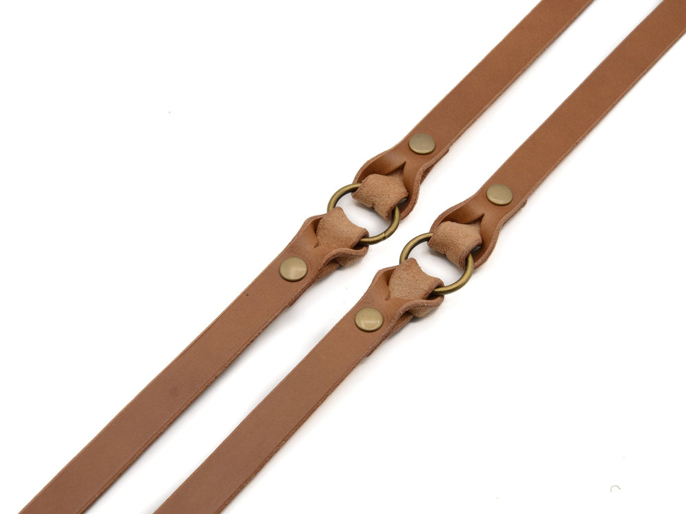 "Zwei braune Lederleine Waldstreuner mit goldfarbenen Metallringen und Druckknöpfen zur Befestigung."