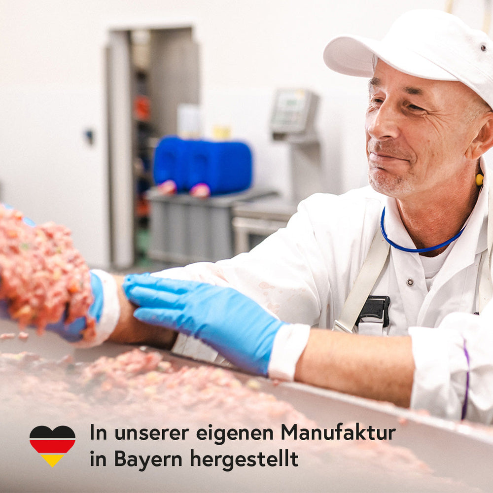 Mann in Lebensmittelverarbeitung mit Hühnerfleisch für FRED Huhn mit Reis, zeigt professionelle und hygienische Zubereitung.