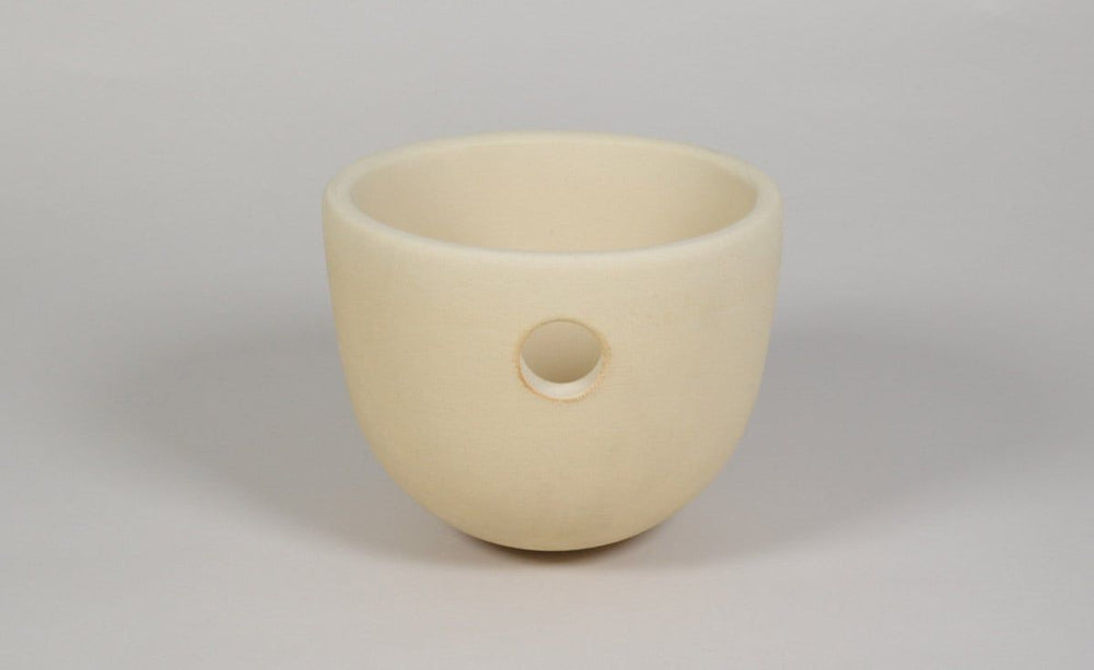 Kreismäßiger, beige Keramiktopf mit rundem Loch für Nisthöhlen-Ersatzteil in schlichtem, modernem Design.