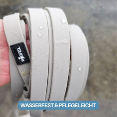 Hand mit wasserfesten Gurten der Schleppleine WOOFLEX® und Sicherheitskarabiner in neutralen Farbtönen.