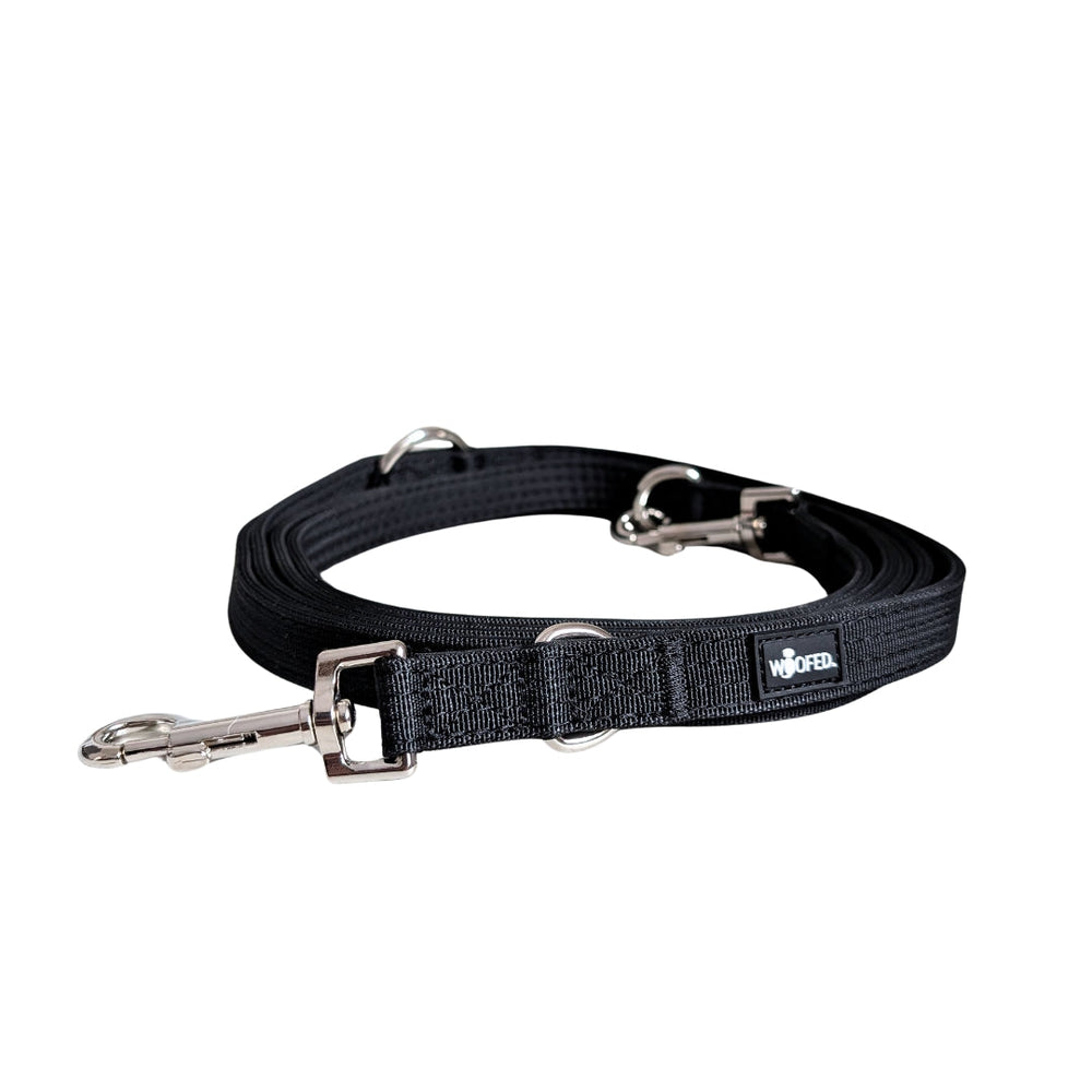 Schwarze Nylon Hundeleine mit zwei Karabinerhaken, verstellbarer Schlaufe und WOOFED-Logo. Ideal für Spaziergänge.