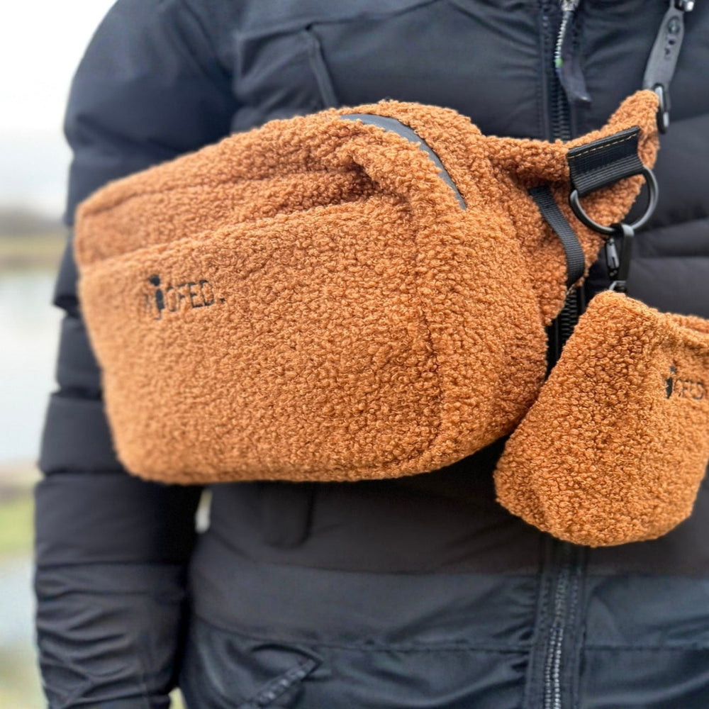 Orangene multifunktionale Gassitasche aus Teddyfell als Bauchtasche und Schultertasche an einer Person getragen.