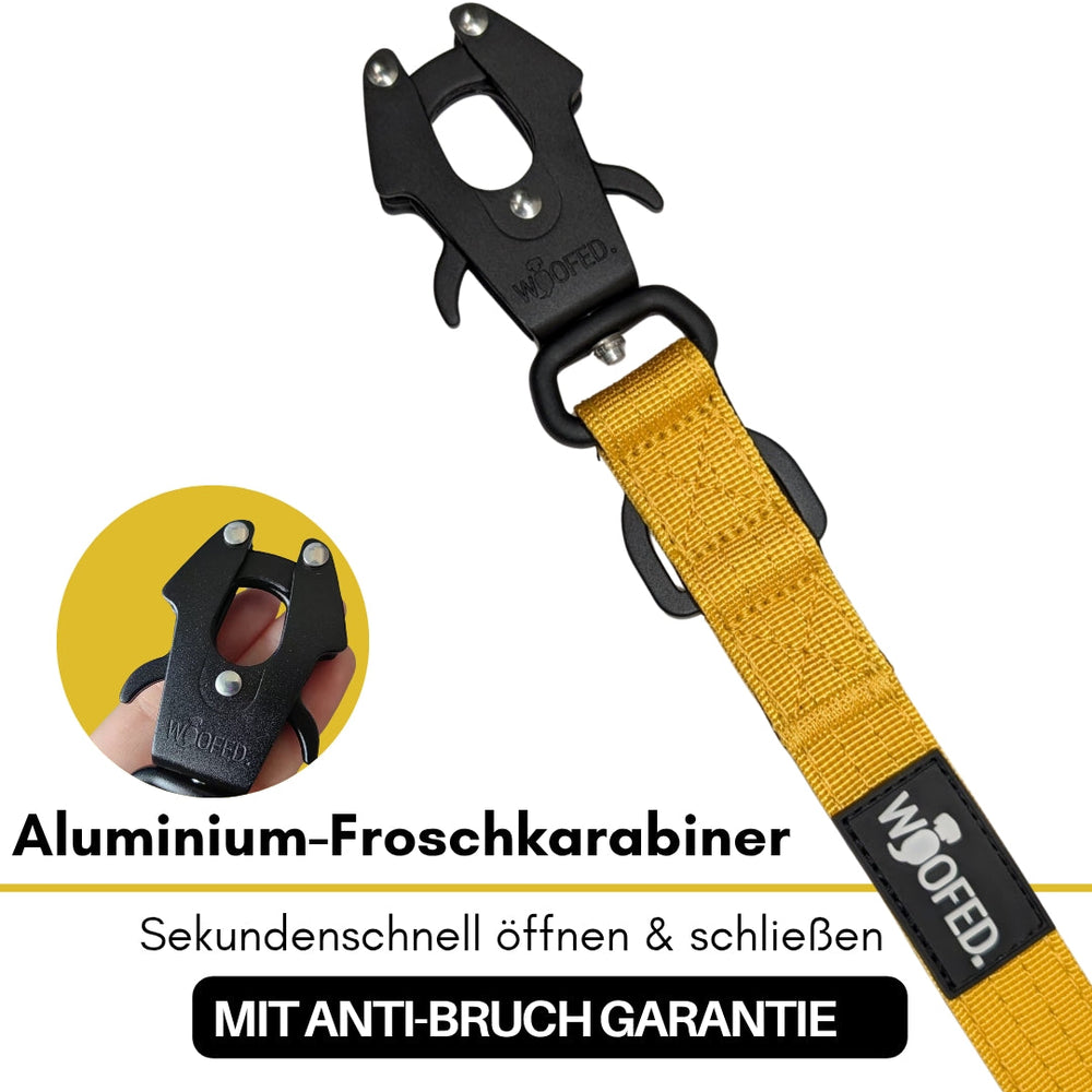 Schwarzer Aluminium-Froschkarabiner an gelbem Textilband mit schneller Öffnungsmechanik und Anti-Rutsch-Funktion.