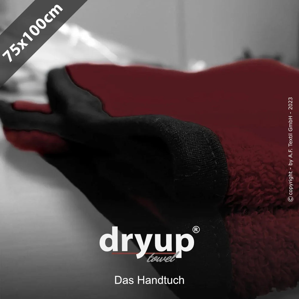 Rotes Dryup® Handtuch 75x100 cm mit schwarzem Rand und Logo auf unscharfem, neutralem Hintergrund.