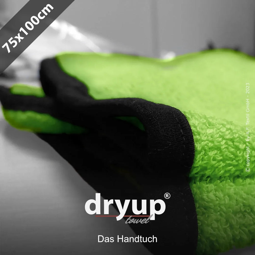 Weiches, leuchtend grünes Dryup® Handtuch mit schwarzen Kanten, 75x100 cm, auf einer Oberfläche liegend.