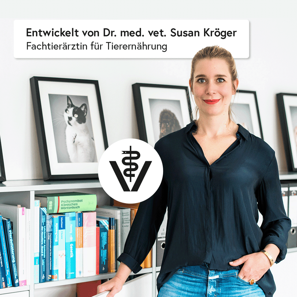 Frau in schwarzem Oberteil lächelt vor Bücherregal mit Tierfotos und Tierernährungsbüchern, zeigt FELIA VET Low Protein.