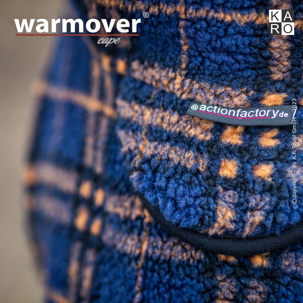 Blau-orange kariertes warmover® Cape aus flauschigem Stoff mit gut sichtbarem Logo und Etikett für die Website.