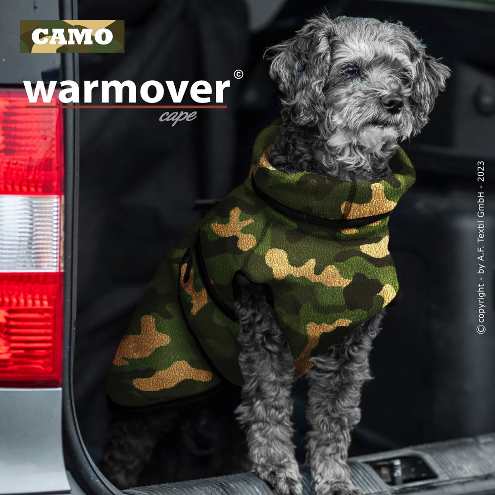 Kleiner grauer Hund im Camouflage-Mantel sitzt im Kofferraum, bereit für Abenteuer mit dem warmover© cape mini.
