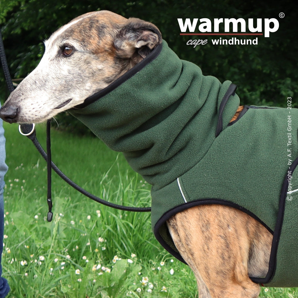 Windhund in grünem Fleecemantel von warmup© cape pro, stehend in grasgrüner Umgebung.