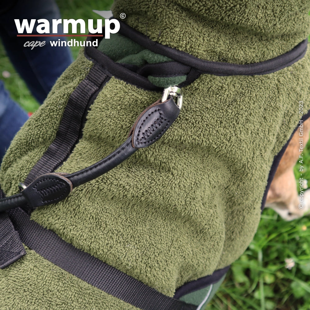 Olivgrüner Hundemantel für Windhunde aus flauschigem Material mit Riemen im Hintergrund.