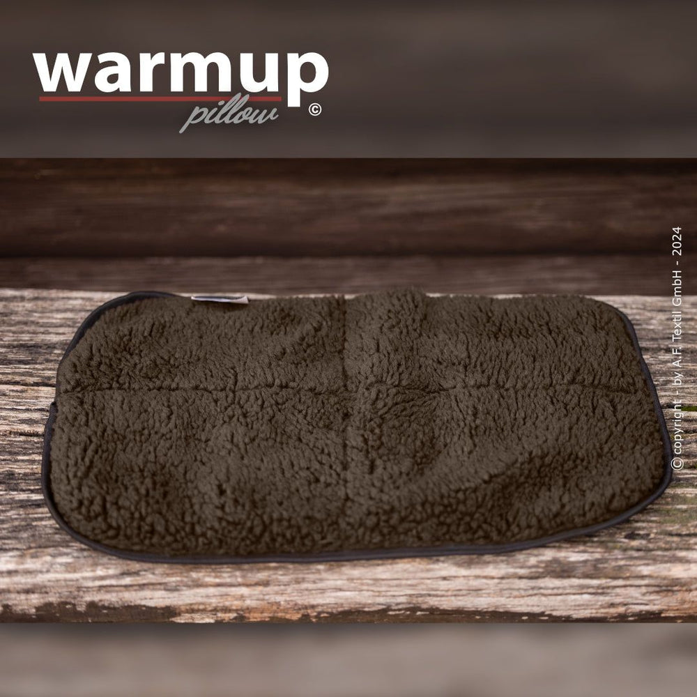 Rechteckiges warmes Kissen in plüschiger Textur auf Holzoberfläche mit sichtbar markiertem "warmup pillow"-Logo.