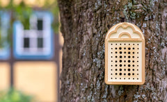 "Braunes Wildbienenhaus mit Nistlöchern, befestigt an einem Baum für sicheren Insektenschutz und Förderung der Biodiversität."
