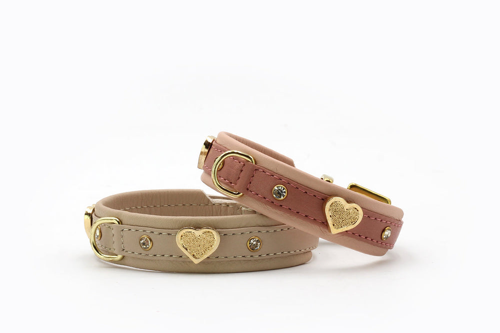 Zwei elegante Hundehalsbänder aus Leder in Beige und Rosa mit goldfarbenen Herzen, ideal für stilvolle Hunde.