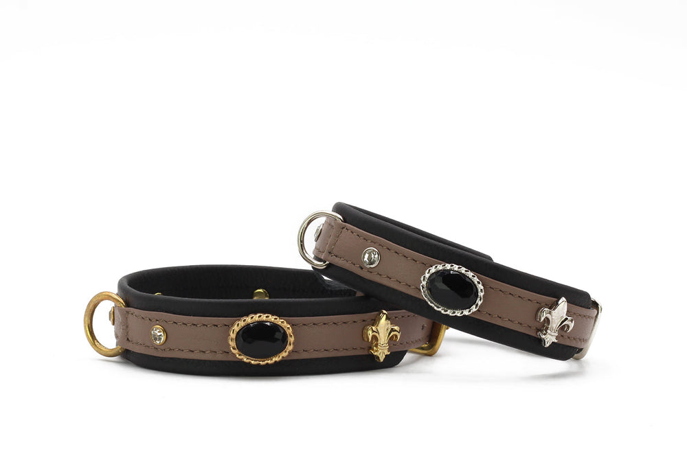 Zwei elegante Armbänder in Schwarz und Beige mit Fleur-de-Lis Motiven und schwarzer Steinfassung.